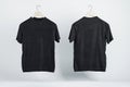 Two blank black t-shirts on wooden hangers with copyspace for your logo on abstract light background. 3D rendering Royalty Free Stock Photo