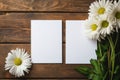 two blank cards mockup on wooden background surrounded by daisies flowers, template white sheet of paper for design Royalty Free Stock Photo