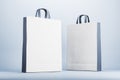 Two blank grey and white eco friendly paper bags on light surface. Mock up Royalty Free Stock Photo
