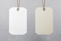Two blank hanging tags: empty white and eco friendly beige made from recycled kraft paper at grey wall background. Recycle concept Royalty Free Stock Photo