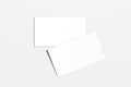 Two blank, rectangular business cards are arranged in an overlapping diagonal pattern on a light gray background Royalty Free Stock Photo
