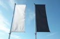 Two blank vertical banners, one white, one black, fly against clear blue sky with scattered clouds. Empty flags offer ample space Royalty Free Stock Photo