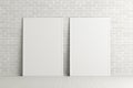 Two blank vertical posters. frame mock up standing on white floor next to white brick wall. Clipping path around posters.
