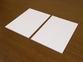 Two blank white papers on a wooden background