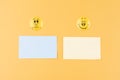 two blank writing papers and happy and sad smiley face on a yellow background. Royalty Free Stock Photo