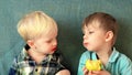 Two blond brother boys eating fresh green apple with great appetite smiling happily, close up view