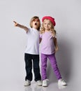 Two blond kids baby girl and boy in stylish clothing standing, hugging each other and pointing at something, singing