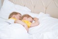 two blonde boys twins sleeping hugging on white bedding Royalty Free Stock Photo