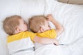 two blonde boys twins sleeping hugging on white bedding Royalty Free Stock Photo