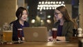 Two blonde and brunette women friends discussing plans with laptop in bar Royalty Free Stock Photo