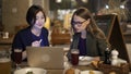 Two blonde and brunette women friends with laptop in bar Royalty Free Stock Photo