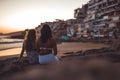 Blonde and brunette women sitting on rocks in Morocco, Taghazout enjoying the sunset