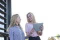 Two blonde students friends laughing using mobile phone and tablet Royalty Free Stock Photo