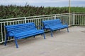 two blue benches stand on a pier near the sea with reeds Royalty Free Stock Photo