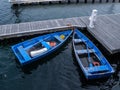 Two Old Blue Row Boats in the Water Tied to a Wooden Dock Royalty Free Stock Photo