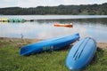 The two blue boats are on the shore as an orange boat is on the lake. Royalty Free Stock Photo