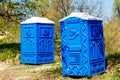 Two Blue Cabines Of Chemical Toilets In Park at sunny Summer Day