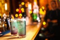 Two blue cocktails with lemon on the bar, blurred background.