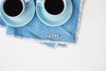 Two blue coffee cups on blue napkin with the words happy