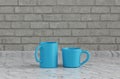 Two blue coffee cups side by side on a front view kitchen counter top with gray tiled brick wall, 3d Rendering, close-up view