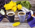 Two blue cups of coffee and a bouquet of yellow tulips. Spring still life with books and a scarf Royalty Free Stock Photo