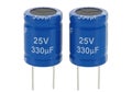 Two blue cylindrical capacitors rated at 25 volts and 330 microfarads each Royalty Free Stock Photo