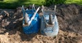 Two blue dirty wheelbarrows turned upside down in the dirt