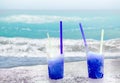 Two blue drift-ice with straw on the beach. In the background is blue sky, palms, sea nd sandy beach. This is situated in tropical