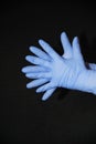 Two blue gloved hands, palms against palm, fingers offset, on black background