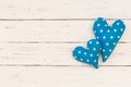 Two blue hearts on white wooden background