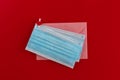 Two blue medical face masks and pink envelope fastened with a clothespin with a heart on red background. Royalty Free Stock Photo