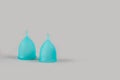 Two blue menstrual cups on grey background with copyspace for text or creative presentation. Women health and zero waste