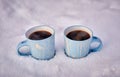 blue mugs of steaming coffee in the snow. winter romatic