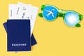 Two blue passports, boarding pass, flight ticket, sunglasses, airplane, sun, blue sky, yellow background, summer holidays, travel Royalty Free Stock Photo