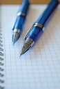 Two blue pens rest on a grid notepad, suggesting a moment of focus and creativity, ideal for jotting down thoughts or Royalty Free Stock Photo