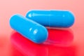 Two blue pills on a red background close-up macro Royalty Free Stock Photo