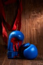 Two blue and red boxing gloves and red bandage against wooden background. Royalty Free Stock Photo