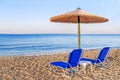 Two blue sunbed, straw umbrella on beautiful beach background Royalty Free Stock Photo