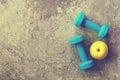 Two blue weights, dumbbells and yellow apple on concrete background. Royalty Free Stock Photo