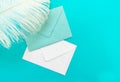blue and white envelopes and a feather isolated against a blue background. Greeting card concept. Copy space.