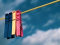 Two blue, yellow and pink clothespegs on a yellow rope