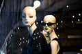 Female mannequin doll displayed n the shop window with city reflections