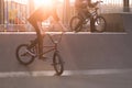 Two bmx cyclists riding a bike on a park skate on the background of the sunset Royalty Free Stock Photo