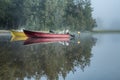Two boats docked at foggy lake, early sunrise, trees, sky reflection in calm water Royalty Free Stock Photo