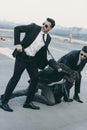 two bodyguards in sunglasses protecting falling businessman Royalty Free Stock Photo