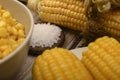 Two boiled ears of corn, corn kernels, coarse salt and raw ears of corn on a wooden table. Fitness diet. Healthy diet. For a sweet Royalty Free Stock Photo