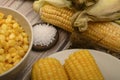 Two boiled ears of corn, corn kernels, coarse salt and raw ears of corn on a wooden table. Fitness diet. Healthy diet. For a sweet Royalty Free Stock Photo