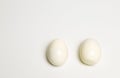 Two boiled peeled eggs on a white background