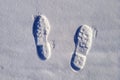 Two boot prints on the surface of the snow