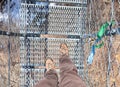 Two boots of the intrepid explorer who walks on the suspension bridge in the void during the mountain hike without suffering Royalty Free Stock Photo